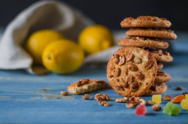 Renkli şekerlenmiş meyve ve sulu turuncu tahta bir masanın üzerinde yatan bir dilim ile yuvarlak portakal bisküvi