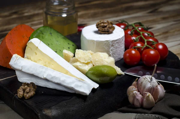 Mezclar el queso sobre fondo oscuro sobre tabla de madera con uvas, miel, nueces, tomates y albahaca. Vista superior . —  Fotos de Stock