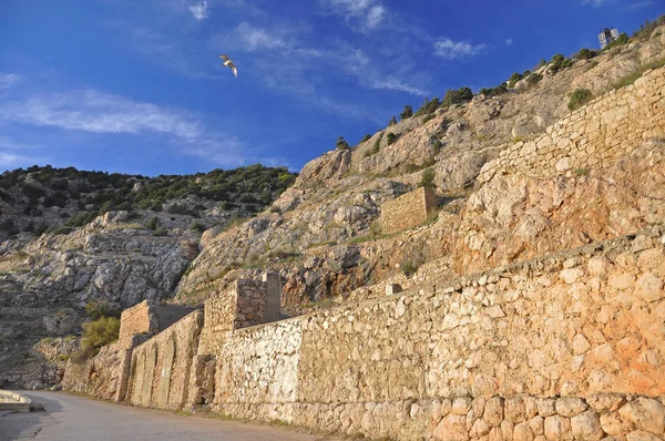 A velha parede fortificada de pedra ergue-se nas montanhas contra o céu azul — Fotografia de Stock