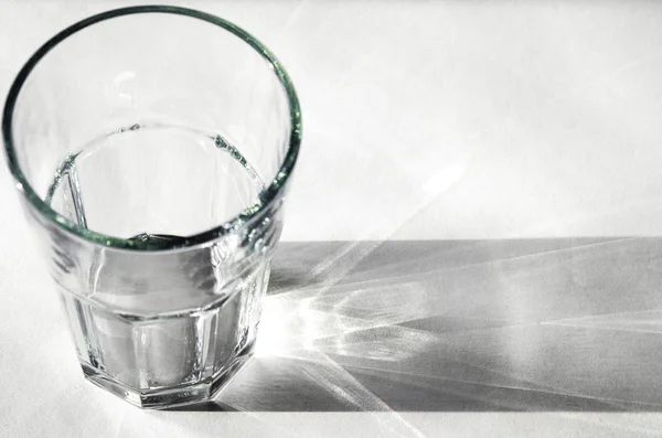 Water glass with strong shadows on white background — Stock Photo, Image