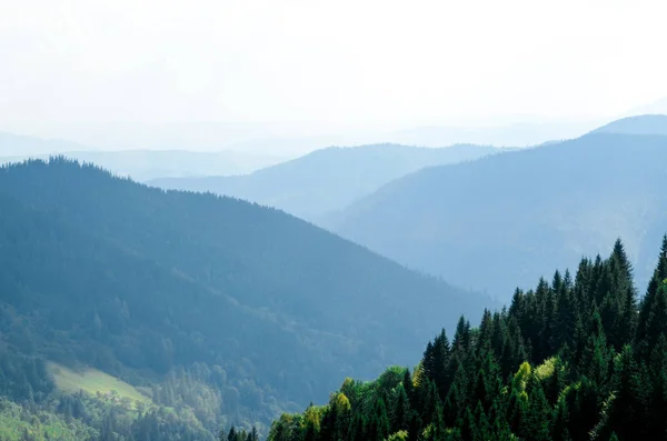 Uma velha casa de madeira de fazendeiro fica em uma montanha de elefantes perto de um palheiro contra o pano de fundo de picos de montanha — Fotografia de Stock