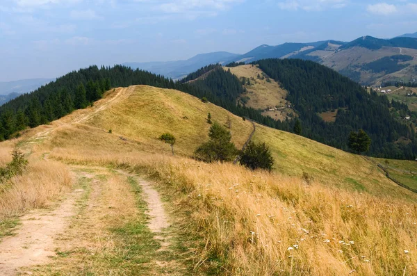 stock image Dirt road high in the mountains that goes down to the village in the valley