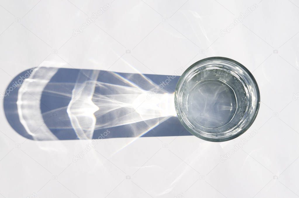 Water glass with strong shadows on white background