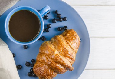Taze siyah frenk üzümü çilek, kırmızı kuş üzümü yanında ahşap bir masa üzerinde çilek ile taze kirli kruvasanlar