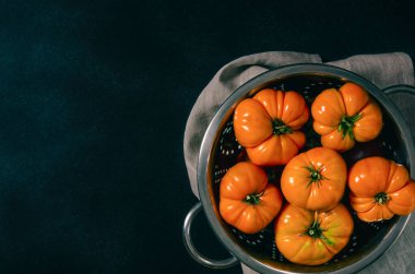 Siyah bir arka plan üzerinde bir kevgir çeşitli domates yıkanmış