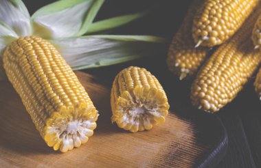 Siyah bir ağaç masada yeşil yaprakları ile sarı sulu mısır