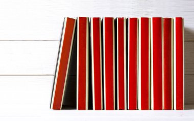 Birçok kırmızı ciltli kitap beyaz ahşap rafta duruyor