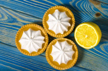 Ahşap bir masada limon dolgulu ve limonlu beyaz hava keki