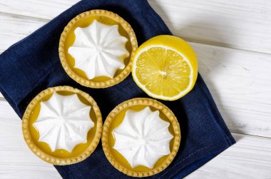 Ahşap bir masada limon dolgulu ve limonlu beyaz hava keki