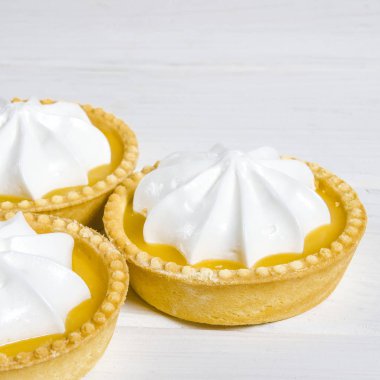 Ahşap bir masada limon dolgulu ve limonlu beyaz hava keki