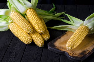 Yeşil yaprakları ile taze sulu sarı mısır bonduel ahşap masa üzerinde yatıyor