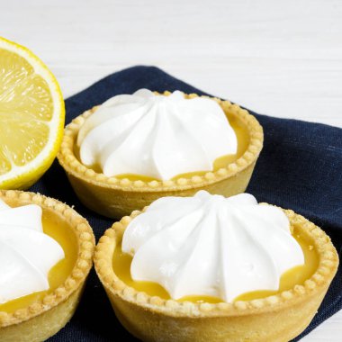 Ahşap bir masada limon dolgulu ve limonlu beyaz hava keki