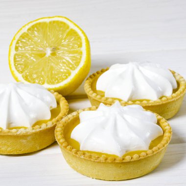 Ahşap bir masada limon dolgulu ve limonlu beyaz hava keki