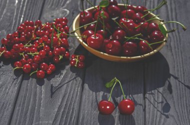 Kırmızı kiraz ve kuş üzümü siyah ahşap arka plan üzerinde yalan