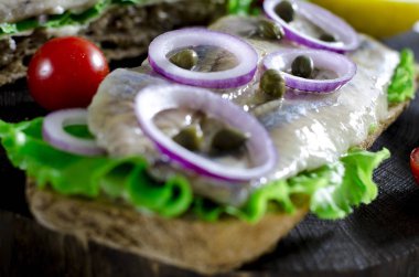 Tuzlanmış ringa balığı, tereyağı ve eski rustik kesme tahtası üzerinde kırmızı soğan ile sandviç. Seçici odak