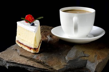 Kiraz, üzüm ve erik ile Meyve kek bir köpük ile kahve beyaz bir fincan yanında vahşi bir taş üzerinde duruyor