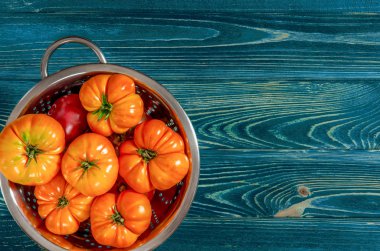 Ahşap bir arka plan üzerinde bir kevgir çeşitli domates yıkanmış