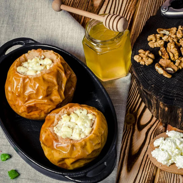Sağlıklı gıda. Süzme peynir ve fındık ile pişmiş elma ahşap bir masa üzerinde siyah bir pişirme çanağı yalan — Stok fotoğraf