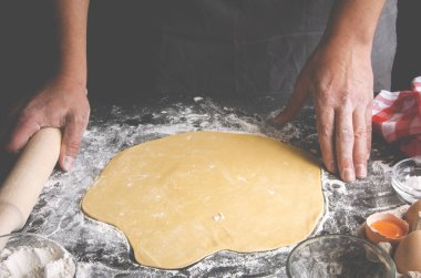 Erkekler siyah bir masada pizza için hamur hazırlar.