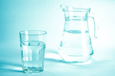 Saf, berrak eritilmiş su bardağı mavi bir zeminde, suyu olan bir couoshma 'nın yanında.