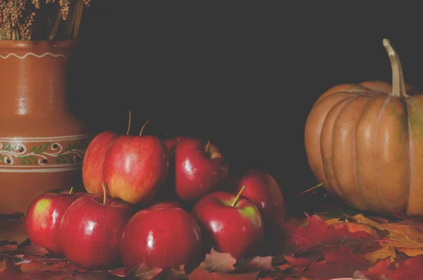 秋の収穫 赤いジューシーなリンゴは黄色の秋の葉のテーブルの上にあります — ストック写真