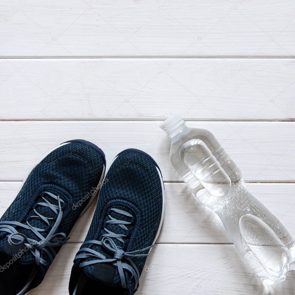 Sports set. Blue women's sneakers, blue dumbbells and white scales stand on a white wooden background