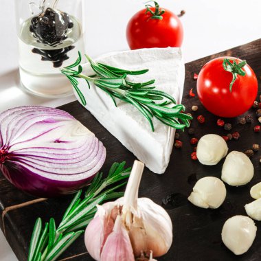 Peynir takımı. Sebze ve biberiyeyle süslenmiş peynir kara tahtada yatıyor.