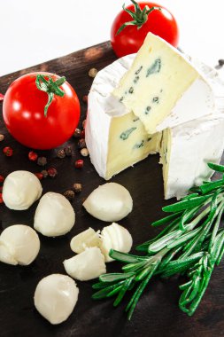 Peynir takımı. Sebze ve biberiyeyle süslenmiş peynir kara tahtada yatıyor.