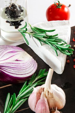 Peynir takımı. Sebze ve biberiyeyle süslenmiş peynir kara tahtada yatıyor.