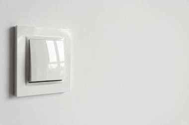 Beyaz bir duvardaki dairede beyaz plastik bir elektrik düğmesi. Onarım