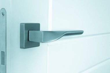 Gümüş metal kapı tokmağı beyaz ahşap bir kapıya monte edilmiştir. Onarım