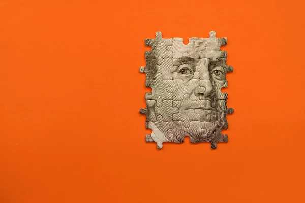 Rompecabezas con el retrato de Benjamin Franklin de billetes sobre fondo naranja — Foto de Stock