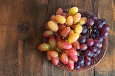 koyu ahşap arka plan üzerinde kahverengi plaka üzerinde üzüm.