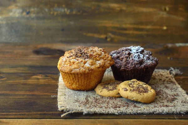 カップケーキとクッキーの暗い背景の木チョコレート — ストック写真