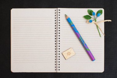 Boş boş not defteri bir renkli kalem ve siyah tekstil zemin üzerine dekor.