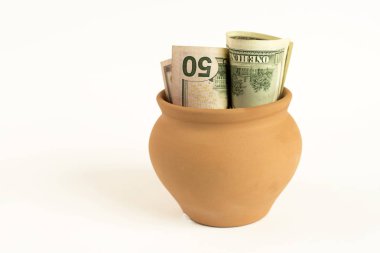 Beyaz arka plan üzerinde banknot ile kahverengi seramik tencere.