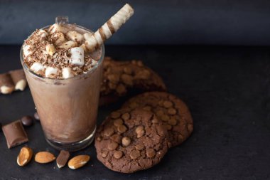 Fincan kakao marshmallows ve çikolatalı kurabiye koyu arka plan üzerinde.