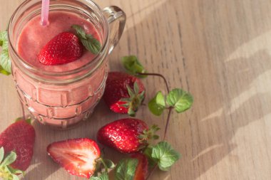 Ahşap masa üzerinde malzemelerle bardaklarda çilek muz Smoothies.