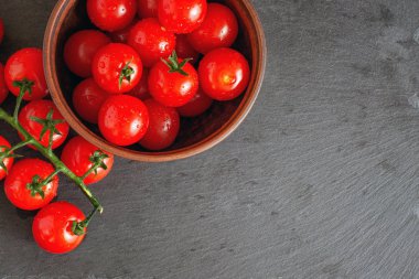 Şube kopya alanı ile siyah taş tabakta taze kiraz domates.