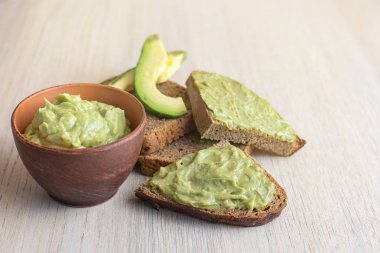 Taze avokado krem kase, ışık ahşap zemin üzerine ekmek dilimleri.
