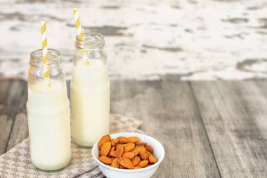 Cam şişeler ve gri ahşap zemin üzerine badem badem sütü.