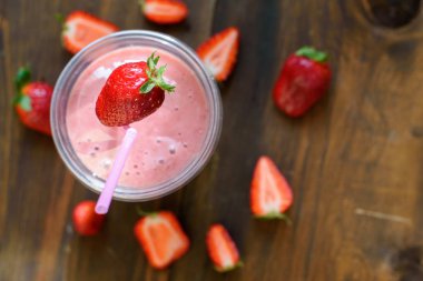 Koyu ahşap masa üzerinde malzemelerle bardaklarda çilek muz Smoothies.