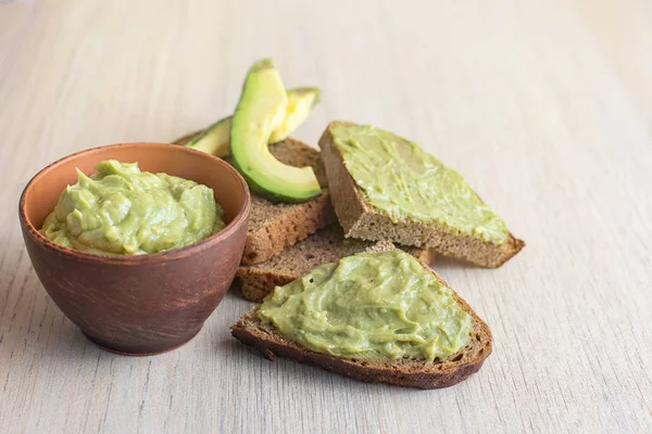 Taze avokado krem kase, ışık ahşap zemin üzerine ekmek dilimleri.