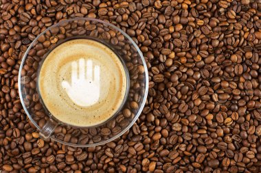 Dur hareketi ile espresso fincan kahve köpük kahve çekirdekleri arka plan üzerinde oturum. Kopya alanı ile.
