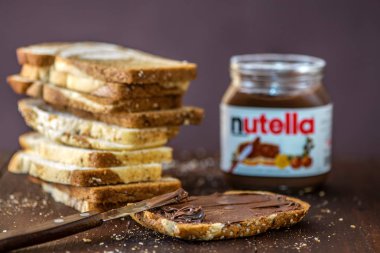 Simferopol, Ukrayna - 3 Ekim 2018: Nutella ve mermer ekmek dilimlenmiş fındık kavanoz rustik ahşap masa üzerinde yayılmış.