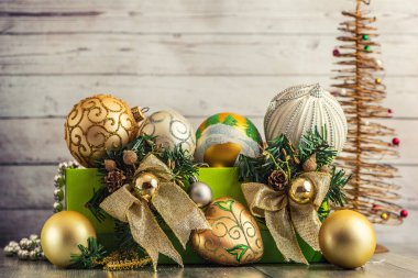Hafif ahşap zemin üzerine yeşil kutusunda Noel süsleri.