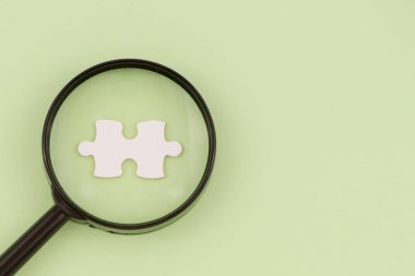 Büyüteç Camı açık yeşil arka planı üzerinde puzzle parçaları eksik için arama. Kopya alanı