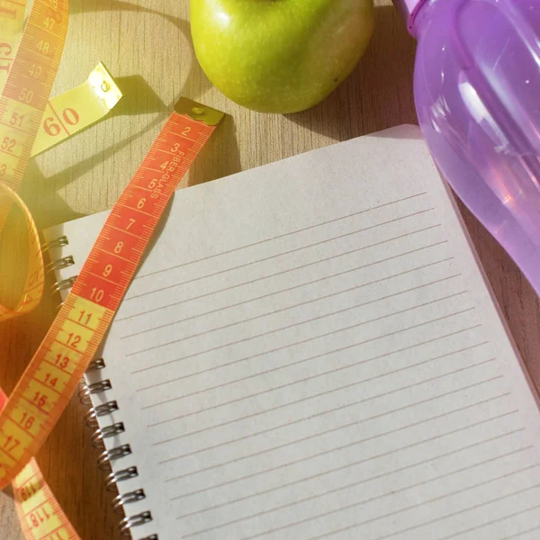 Empty Notepad with apple, tape measure in beautiful light, with copy space.