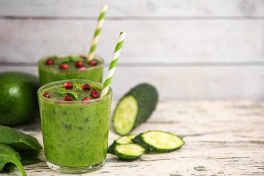 İki ıspanak smoothies. Hafif ahşap masa üzerinde malzemelerle sağlıklı yeşil suyu. Yan görünümü. Kopya alanı ile.