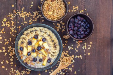 Yulaf ezmesi muz, yaban mersini ve koyu ahşap masa üzerinde elma. Üstten görünüm